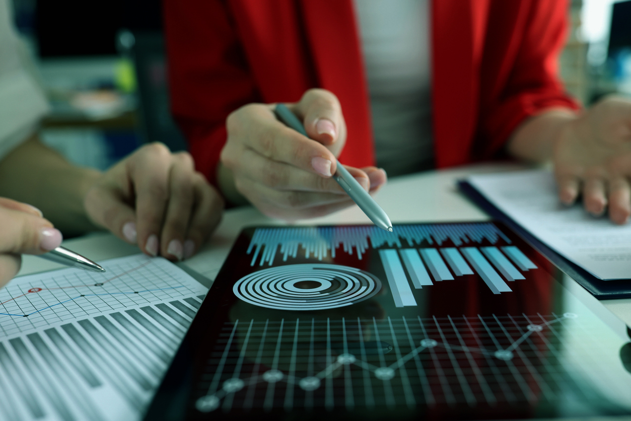 Business women studying charts and diagrams on digital tablet closeup