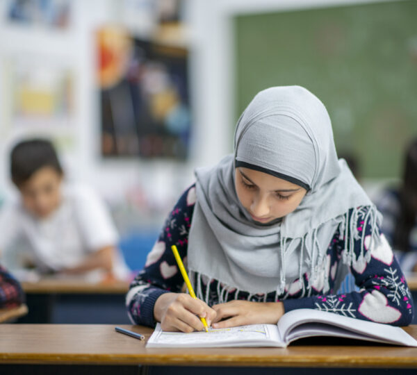 An Afghan elementary student sits at her desk while doing her schoolwork.